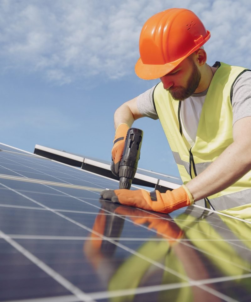 Male worker with solar batteries. Man in a protective helmet. Installing stand-alone solar panel system.